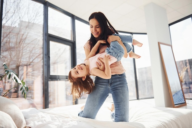 Jovem mãe com sua filha passando fim de semana juntos na cama