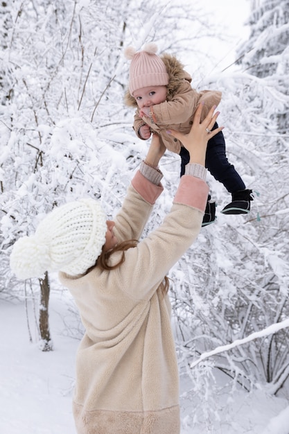 jovem mãe com uma criança pequena brincando na neve