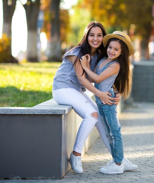 Jovem mãe com uma linda filha andando na rua