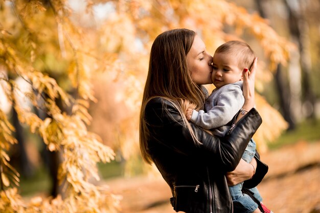 Jovem mãe e bebê menino no parque outono