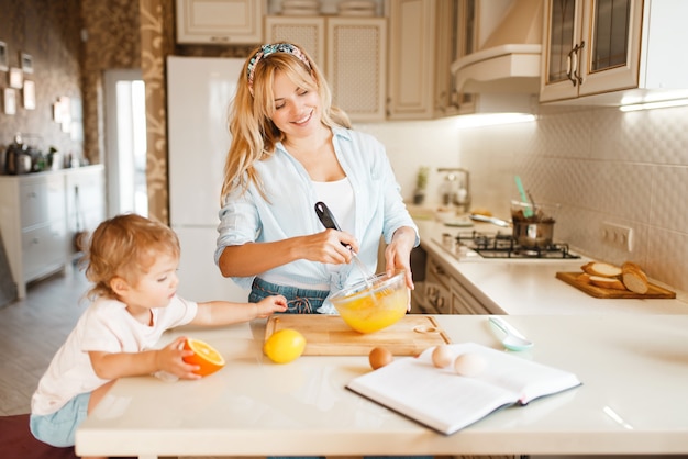 Jovem mãe e filha misturando frutas em uma tigela.