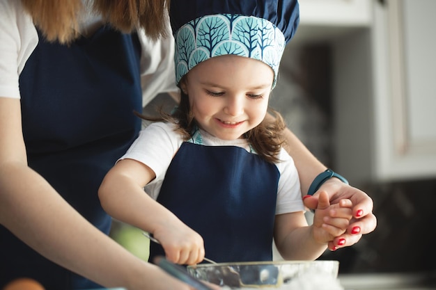 Jovem mãe e filha na cozinha despeje a massa para cupcakes em moldes Mãos fechadas