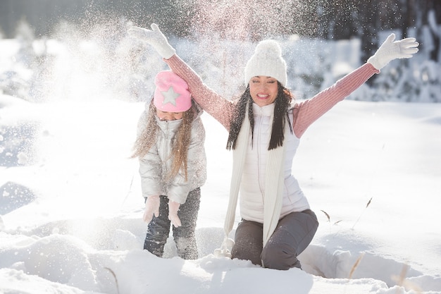 Jovem mãe e filha se divertindo na neve