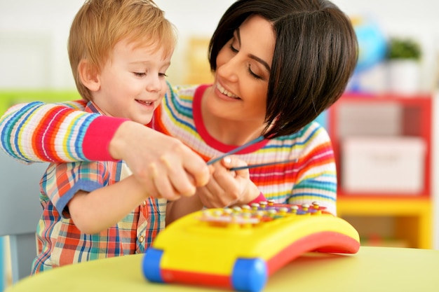 Jovem mãe e filho bonitinho brincando com brinquedo de música em casa