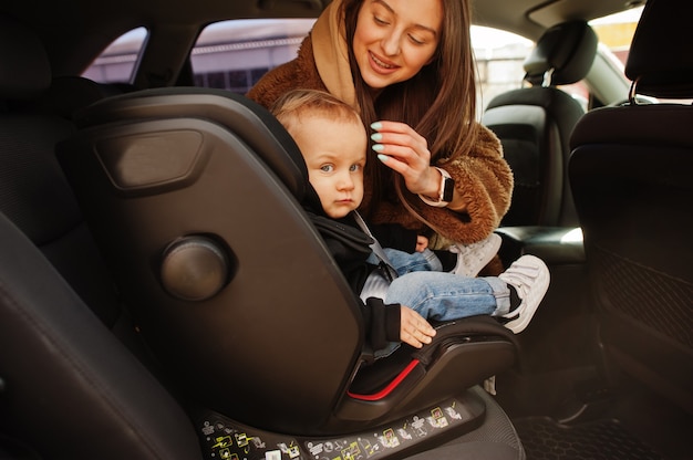 Jovem mãe e filho no carro. Assento de bebê na cadeira. Conceito de condução de segurança.