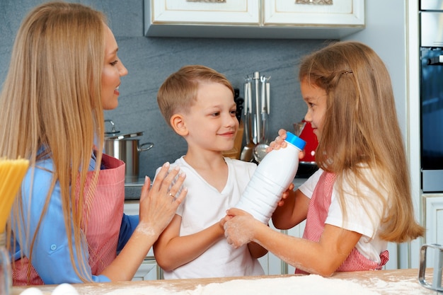 Jovem mãe e seus filhos fofos cozinhando pizza juntos