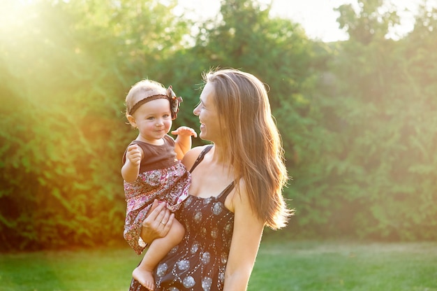 Jovem mãe e sua filha brincando na grama