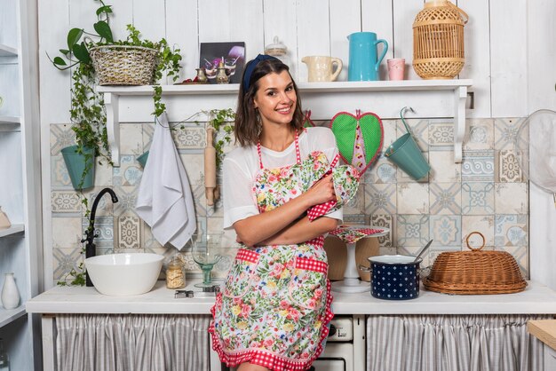 Jovem mãe e sua filha estão cozinhando na cozinha em lindos aventais