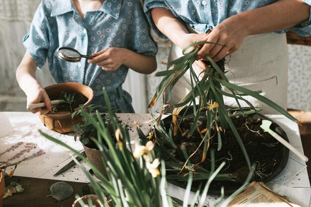 Foto jovem mãe e sua filha pequena em looks de família vestidos estão plantando flores no terraço de primavera em casa jardim mudas crescendo casa de campo varanda maternidade