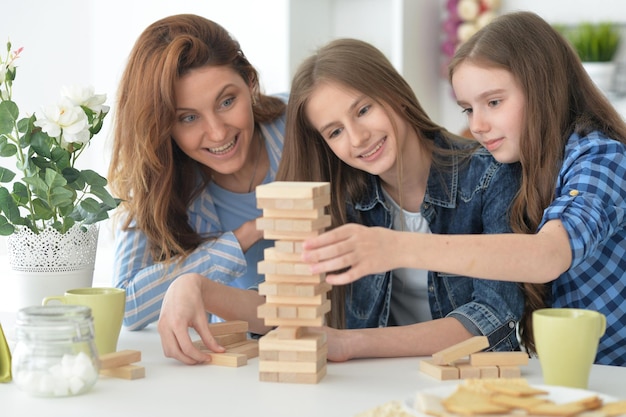 Jovem mãe e suas filhas brincando com blocos de madeira