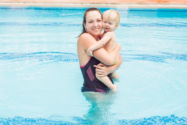 Jovem mãe ensina seu filho a nadar em uma piscina