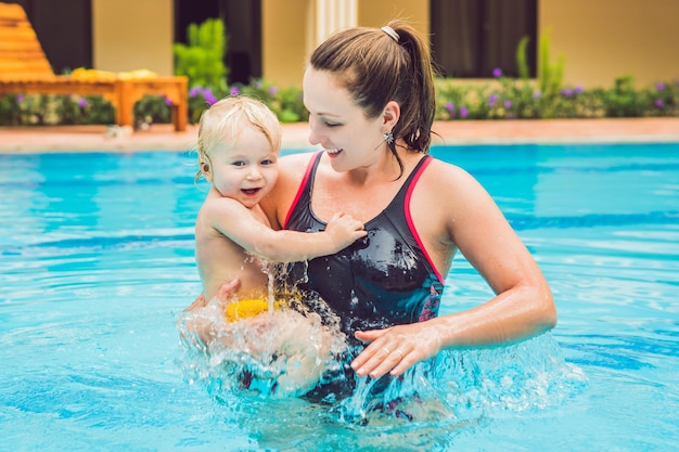 Jovem mãe ensina seu filho a nadar em uma piscina