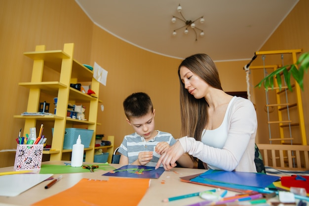 Jovem mãe está fazendo lição de casa com o filho em casa. pais e treinamento