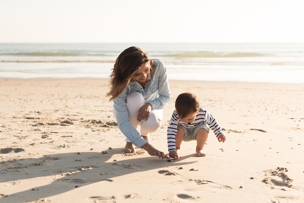 Jovem mãe explorando a praia com criança