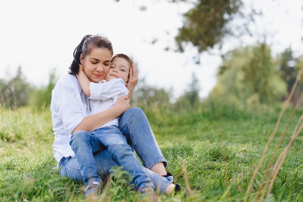 Jovem mãe feliz brincando com seu bebê em um parque em um gramado verde