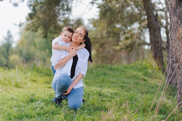 Jovem mãe feliz brincando com seu bebê em um parque em um gramado verde