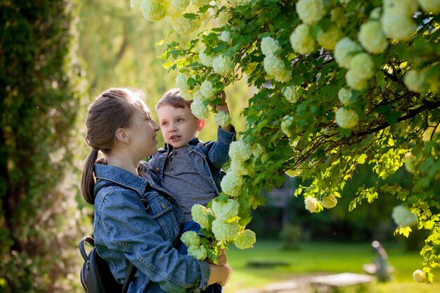 Jovem mãe feliz brincando e se divertindo com seu filho bebê em um dia quente de primavera ou verão no parque