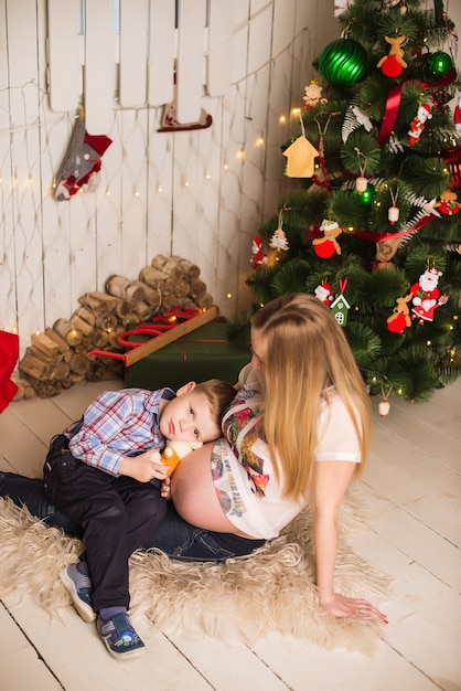 Jovem mãe grávida e criança comemorando o Natal em casa