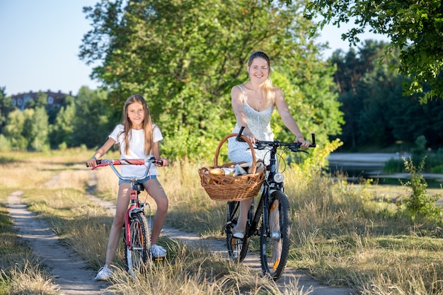 Jovem mãe indo para um piquenique com a filha em bicicletas