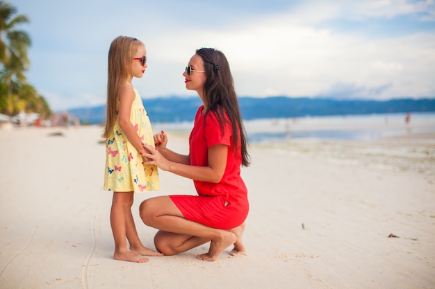 Jovem mãe linda e sua adorável filha ao pôr do sol