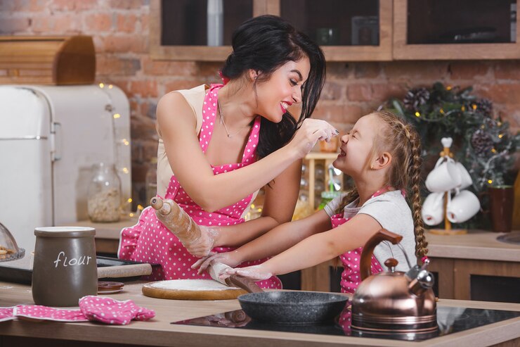 Jovem mãe linda e sua filha cozinhando na cozinha