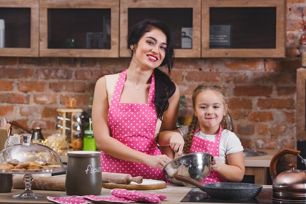 Jovem mãe linda e sua filha cozinhando na cozinha