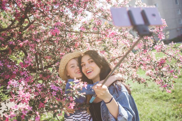 Jovem mãe linda e sua filha fazendo selfie no telefone móvel.