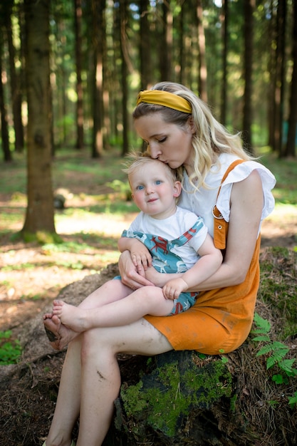 Jovem mãe posando com seu filho engraçado na floresta