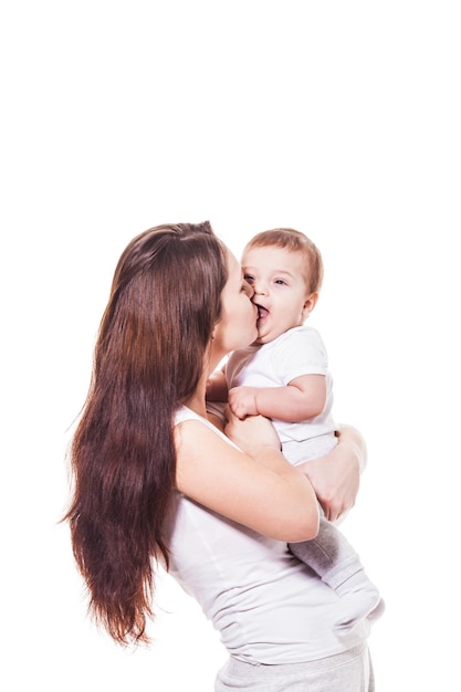 Jovem mãe segurando e beijando seu bebê no fundo branco