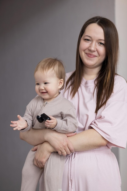 Jovem mãe segurando seu bebê nos braços e sorrindo alegremente