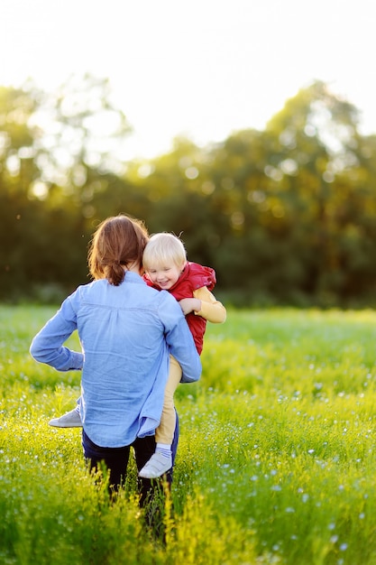 Jovem mãe segurando seu filho pequeno durante a caminhada no campo de flores