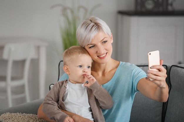 Jovem mãe tomando selfie com seu bebê em casa