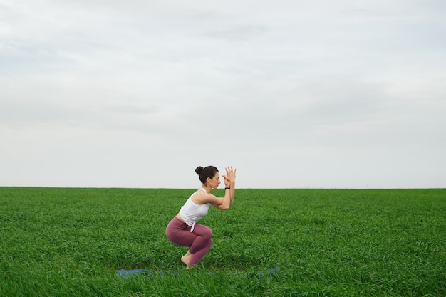 Jovem magro fazendo ioga ao ar livre em um campo verde