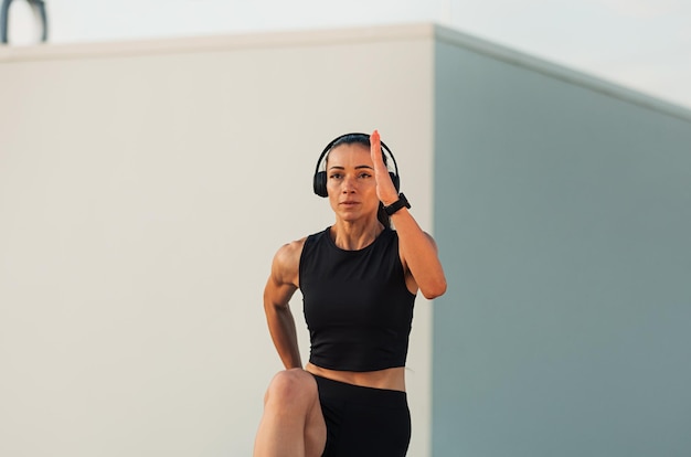 Jovem magro usando fones de ouvido fazendo exercícios de aquecimento