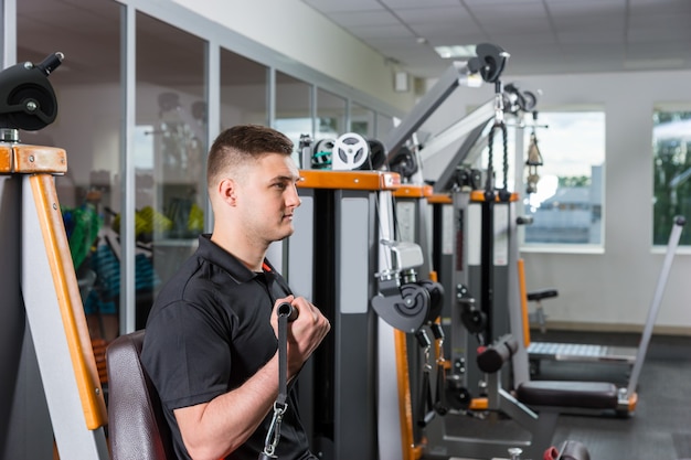 Jovem malhando e fazendo exercícios na sala de ginástica no centro de fitness