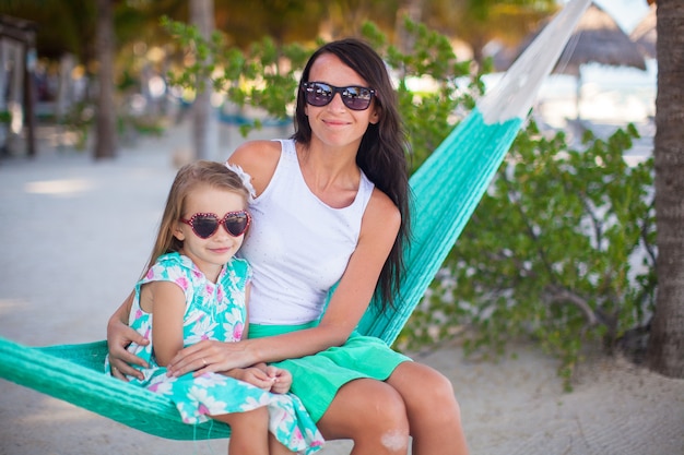 Jovem mamãe e menina de férias tropicais relaxantes na rede