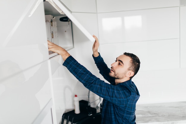 Jovem mão abrir o armário da cozinha com alça, close-up