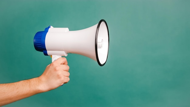 Jovem mão masculina segurando um megafone branco