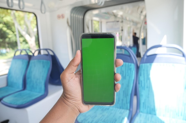 Jovem mão usando smartphone com tela verde dentro de trem de metrô