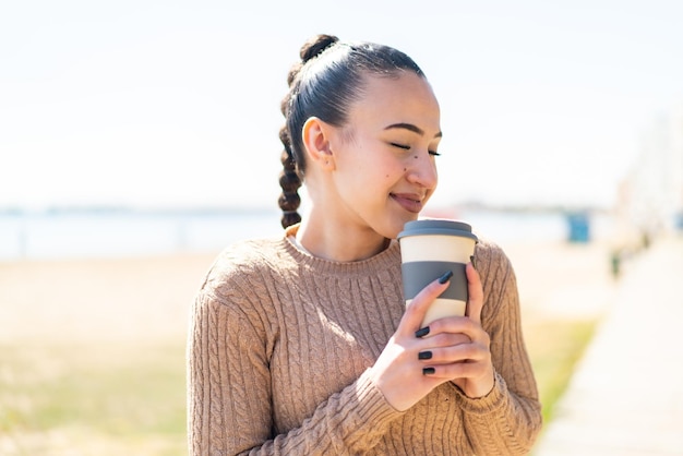 Jovem marroquina ao ar livre segurando um café para viagem