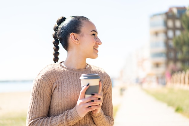 Jovem marroquina ao ar livre segurando um café para viagem