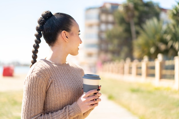 Jovem marroquina ao ar livre segurando um café para viagem