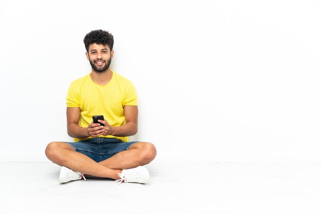 Jovem marroquino bonito sentado no chão isolado