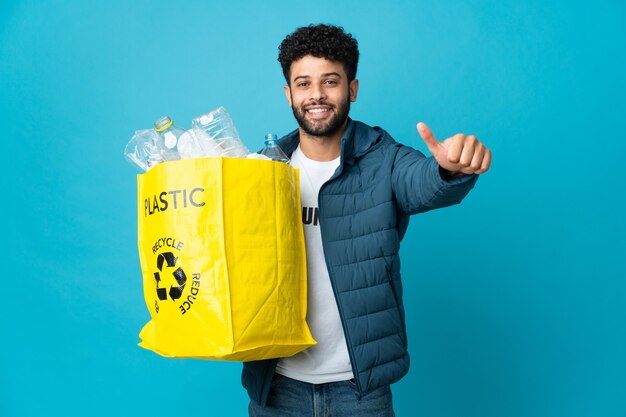 Jovem marroquino segurando um saco cheio de garrafas de plástico para reciclar isolado