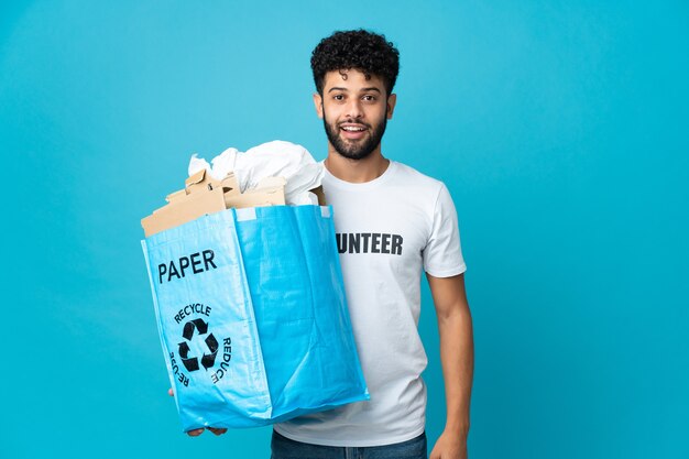Jovem marroquino segurando um saco de reciclagem cheio de papel para reciclar isolado