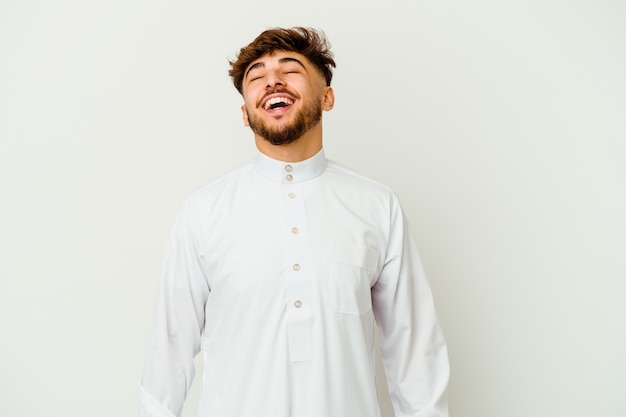 Jovem marroquino vestindo uma roupa típica árabe relaxado e feliz rindo, pescoço esticado, mostrando os dentes.