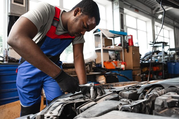 Foto jovem mecânico africano repara carro na garagem de perto