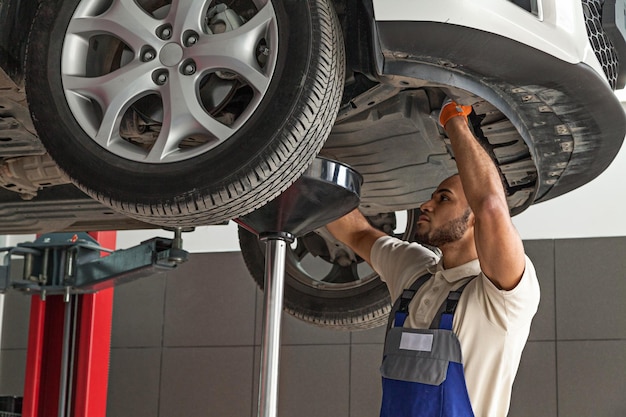 Jovem mecânico consertando carro