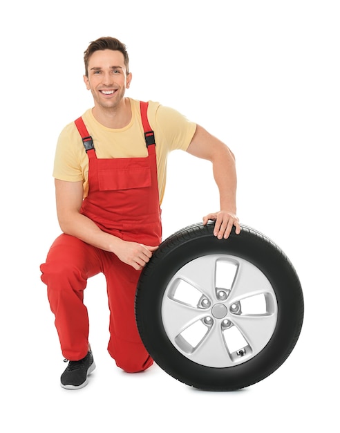 Foto jovem mecânico de uniforme com pneu de carro em fundo branco