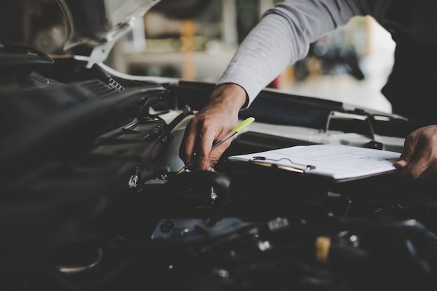 Jovem mecânico segurando a lista de verificação da área de transferência do carro